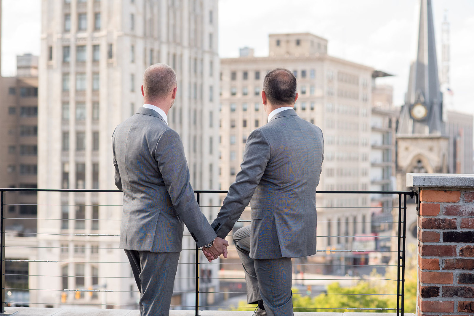 a gay couple hold hands after their wedding in the city of detroit