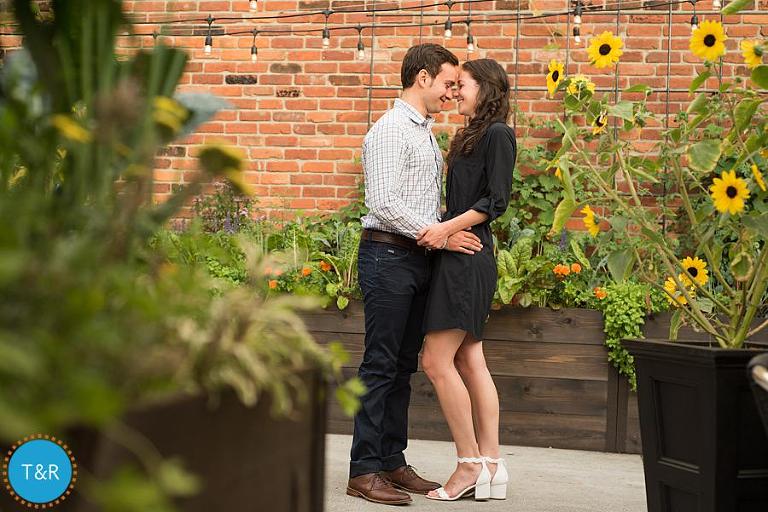 A couple embraces outside a Corktown brick building during their engagement session