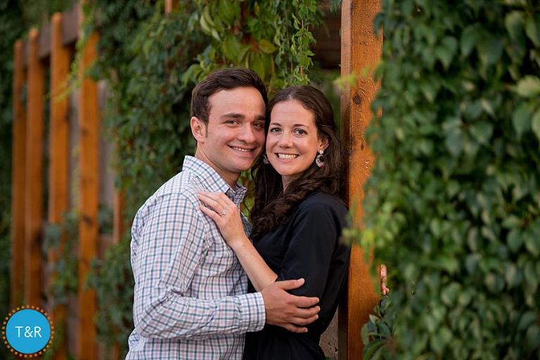 A couple embraces surrounded by an ivy wall