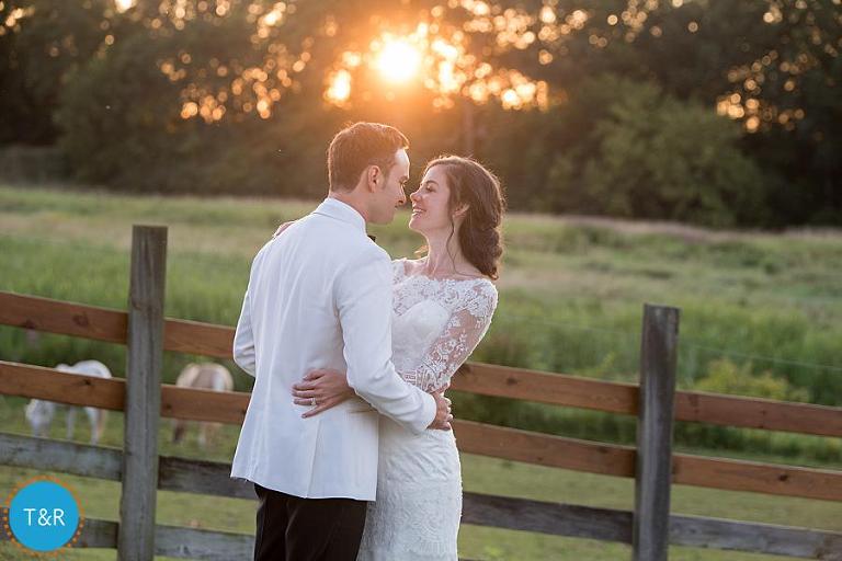 bride and groom embrace with sunset in background at Misty Farm wedding